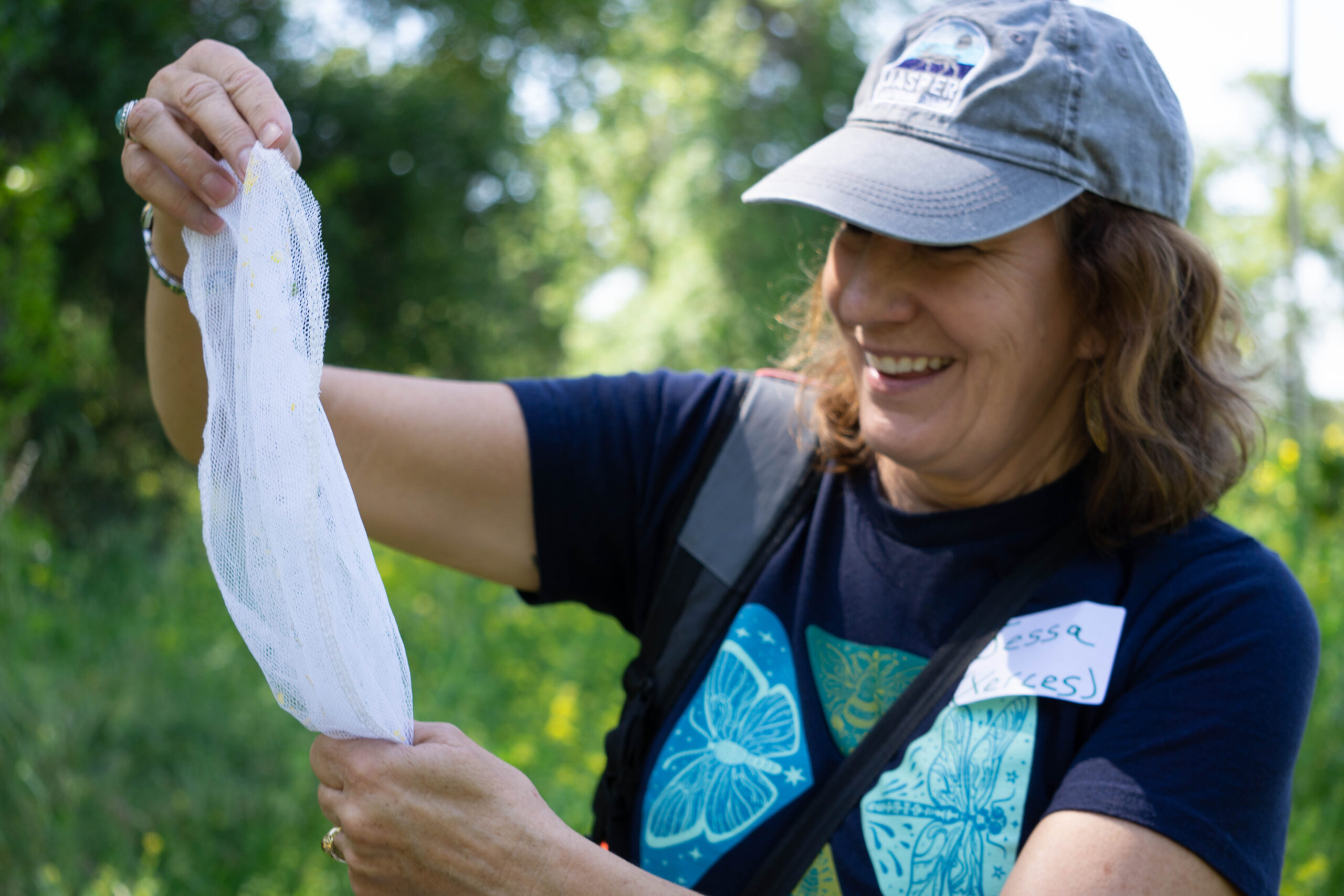 A person with a smile on their face and a bug net in hand.